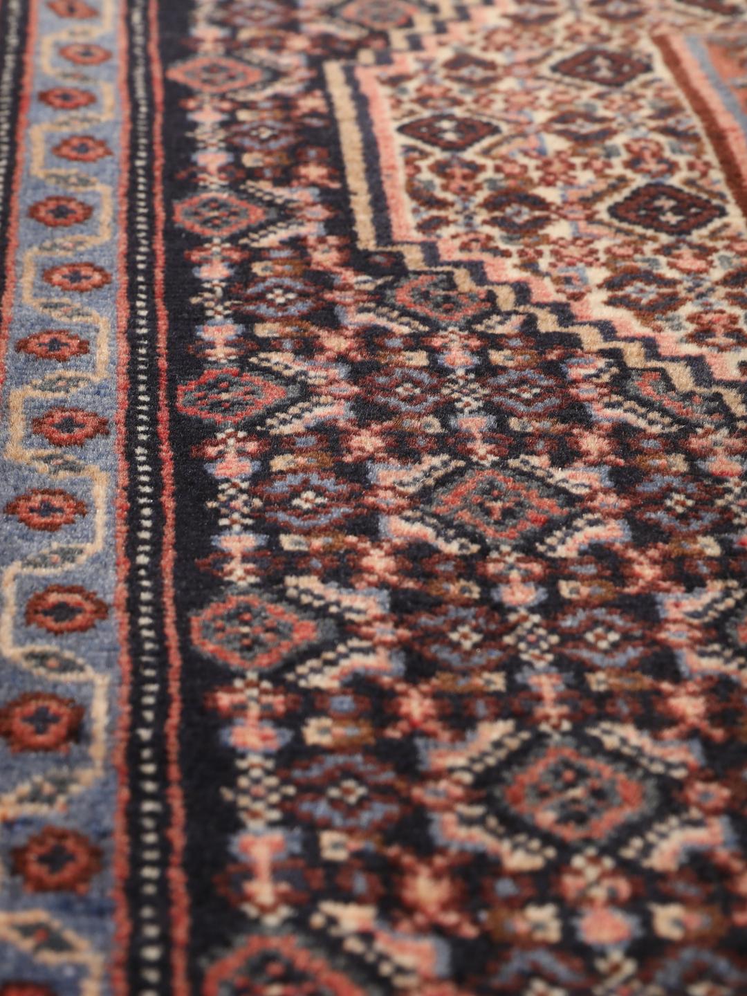 A hand-knotted Senneh rug from the Middle East in dark-blue and dark-red tones.
