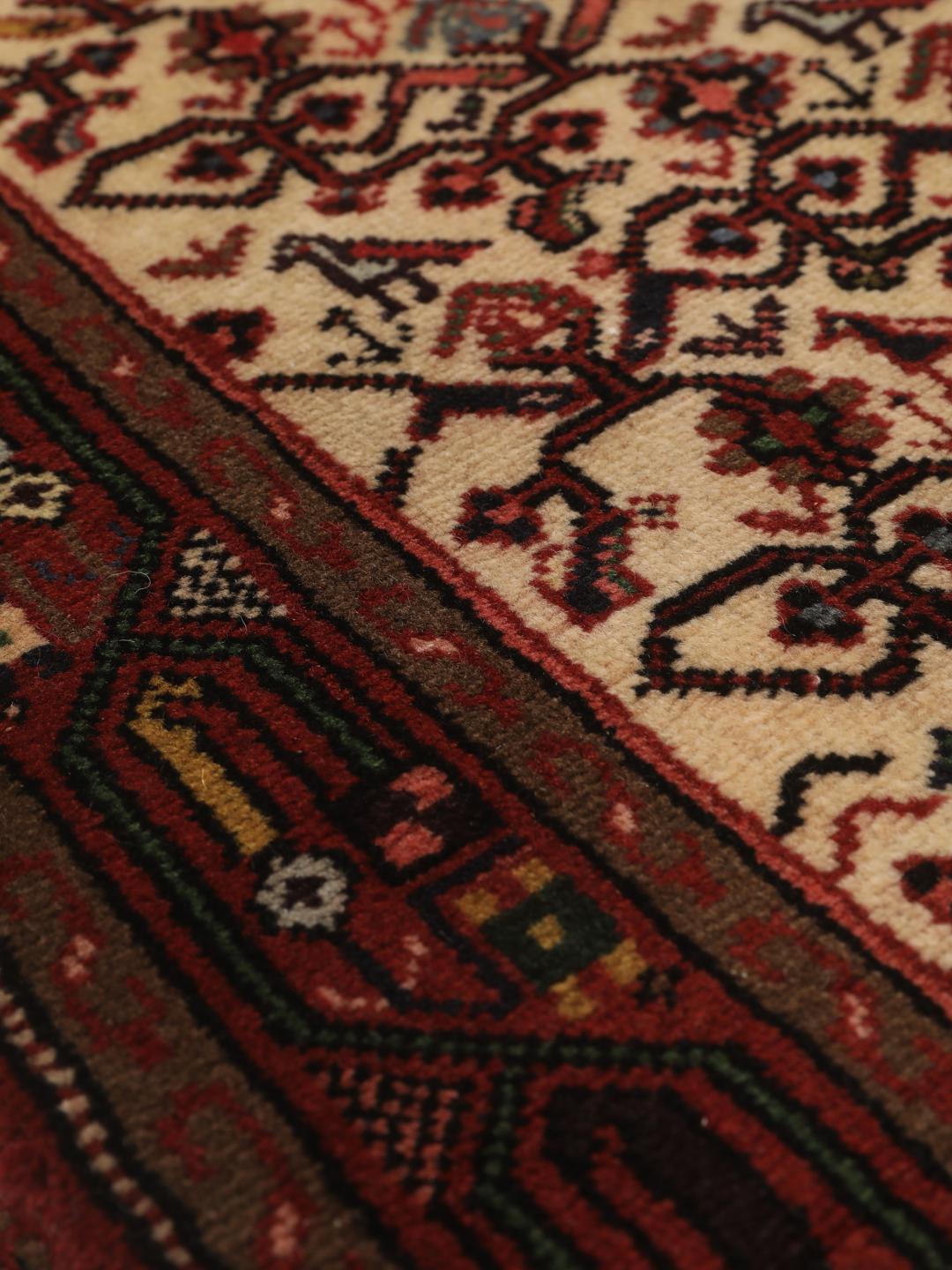 Een handgeknoopte Asadabad loper uit het Midden-Oosten met een rood en beige geometrisch patroon.