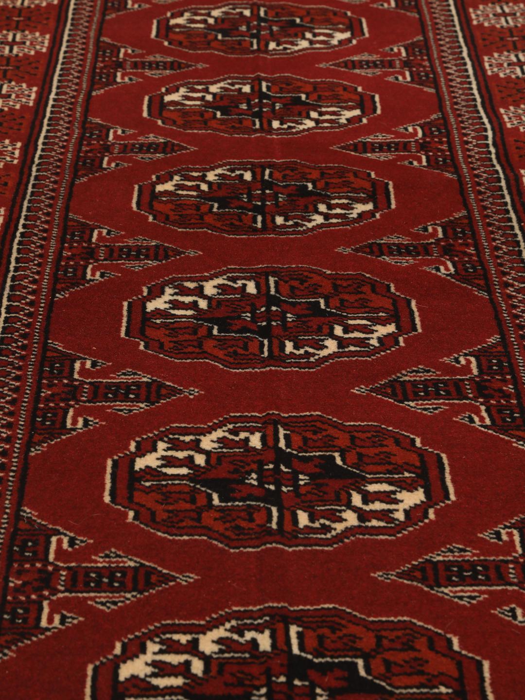 A hand-knotted Middle Eastern Turkaman runner in deep red with geometric medallion patterns.