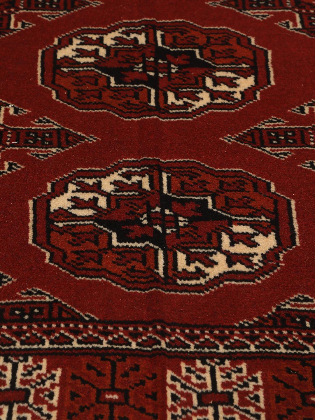 A hand-knotted Middle Eastern Turkaman runner in deep red with geometric medallion patterns.