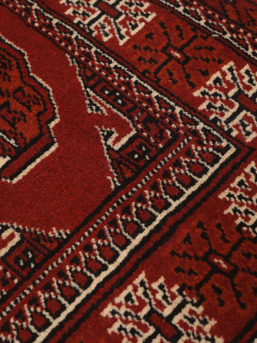 A hand-knotted Middle Eastern Turkaman runner in deep red with geometric medallion patterns.