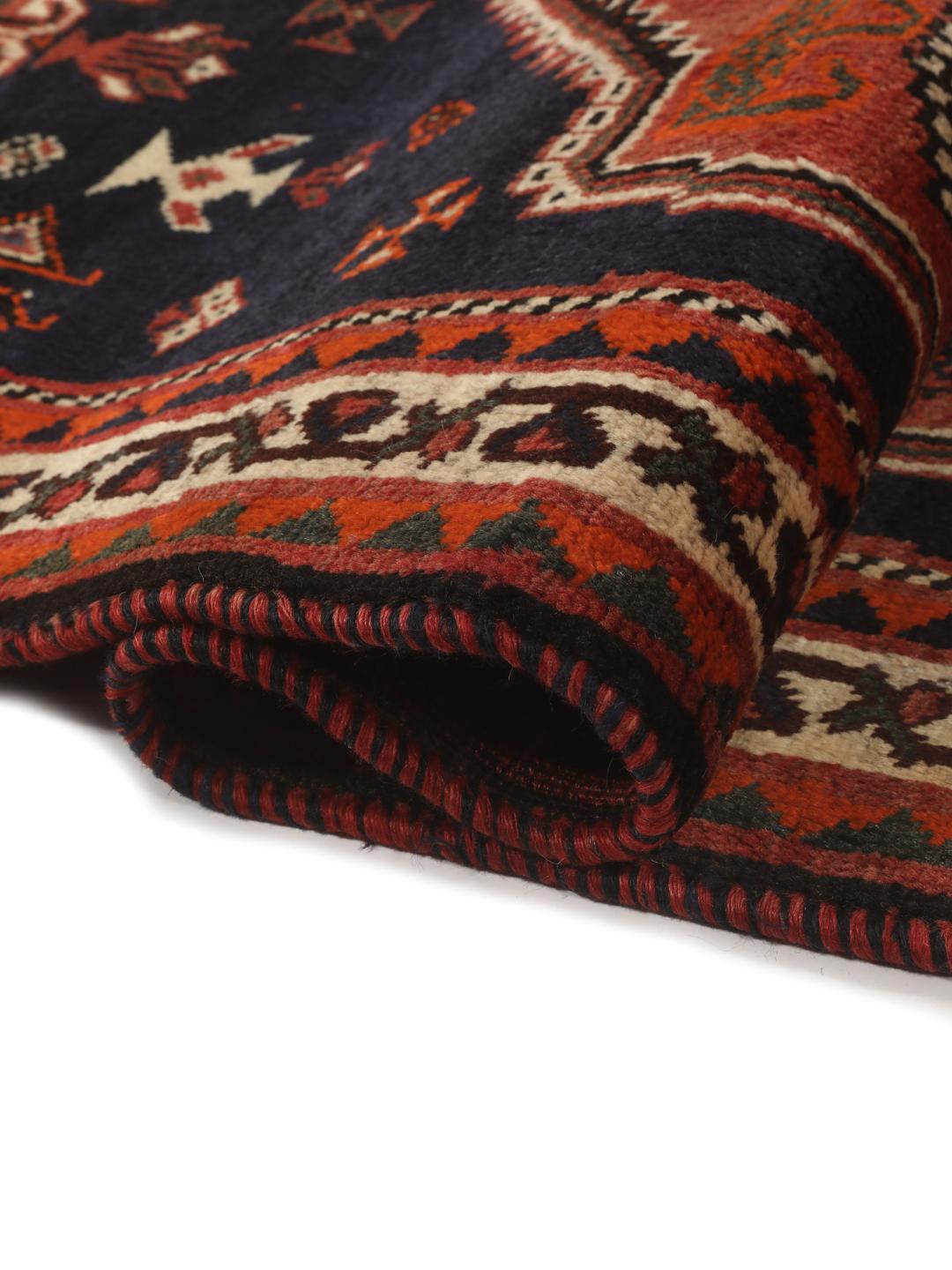 Een rechthoekig handgeknoopt Ghashghai tapijt uit het Midden-Oosten met een donkerrood en donkerblauw palet met geometrische motieven.