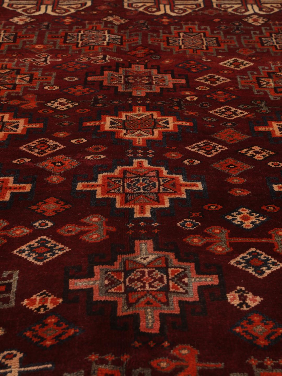 Hand-knotted Qashqai rug from the Middle East featuring geometric patterns in dark red and multicolour wool.