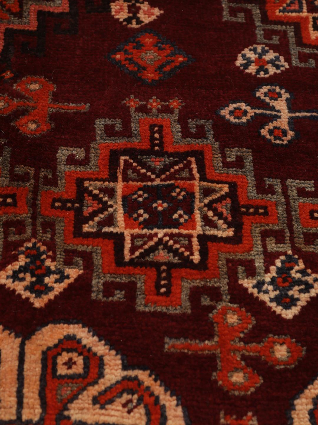 Hand-knotted Qashqai rug from the Middle East featuring geometric patterns in dark red and multicolour wool.