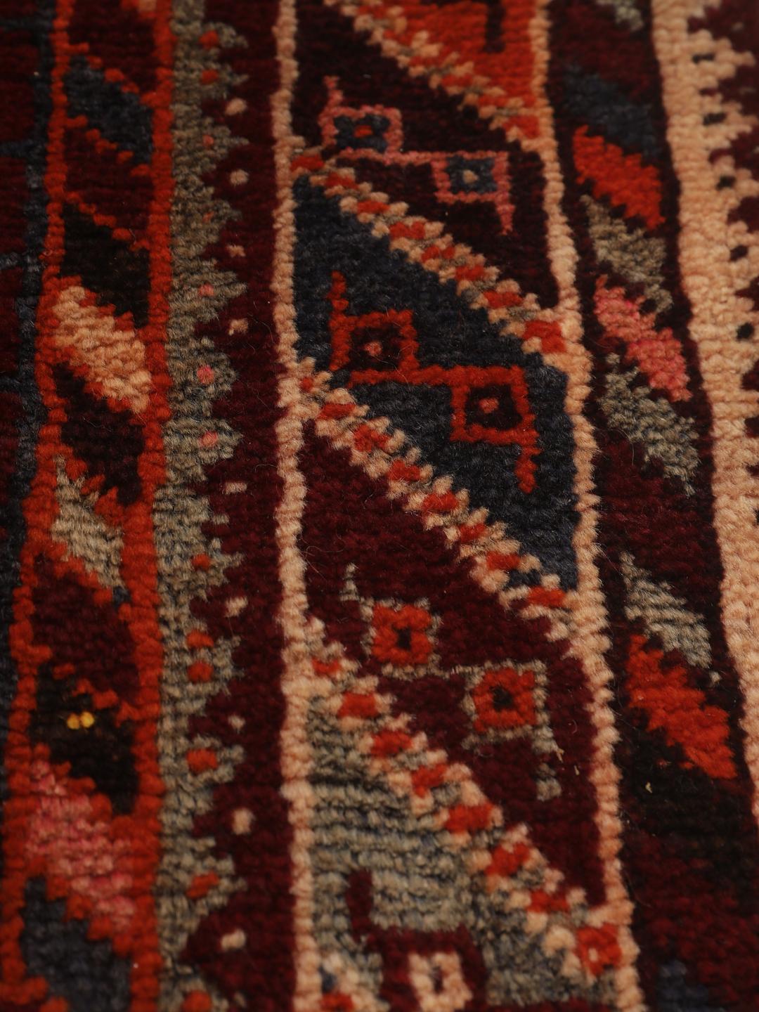 Hand-knotted Qashqai rug from the Middle East featuring geometric patterns in dark red and multicolour wool.