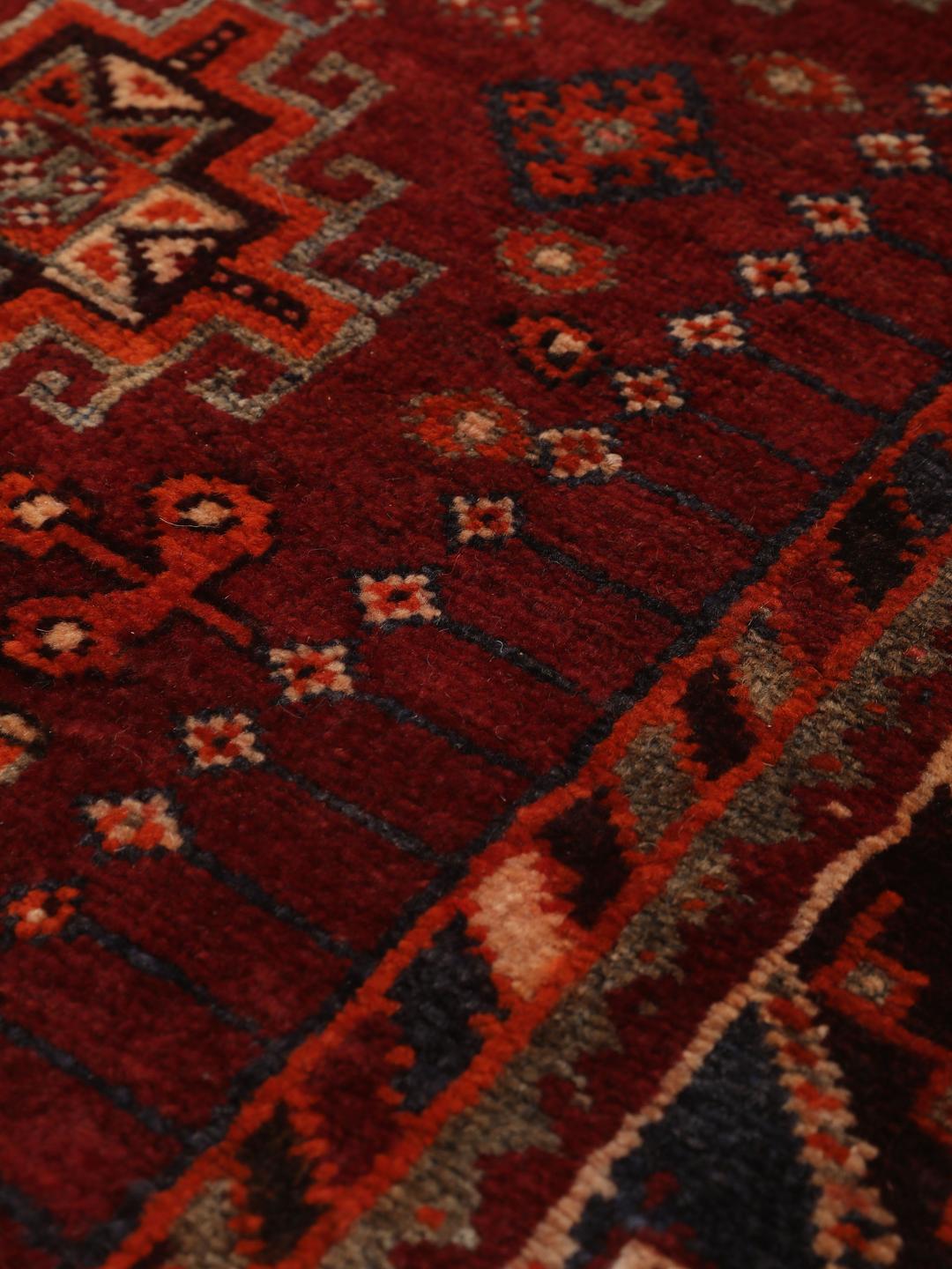 Hand-knotted Qashqai rug from the Middle East featuring geometric patterns in dark red and multicolour wool.