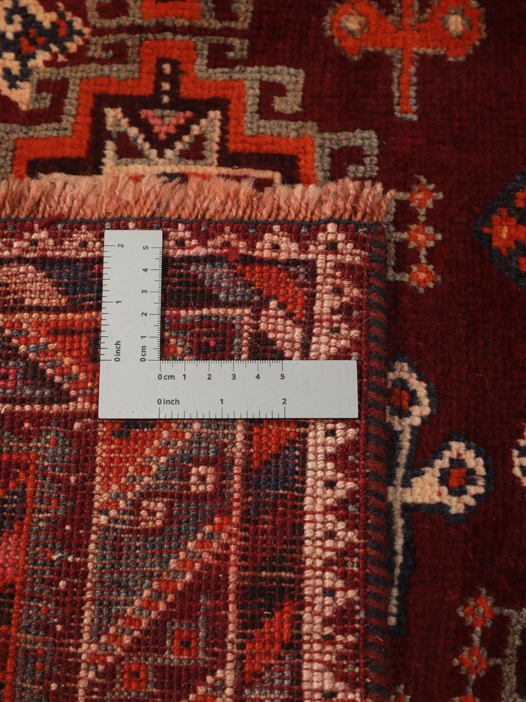 Hand-knotted Qashqai rug from the Middle East featuring geometric patterns in dark red and multicolour wool.