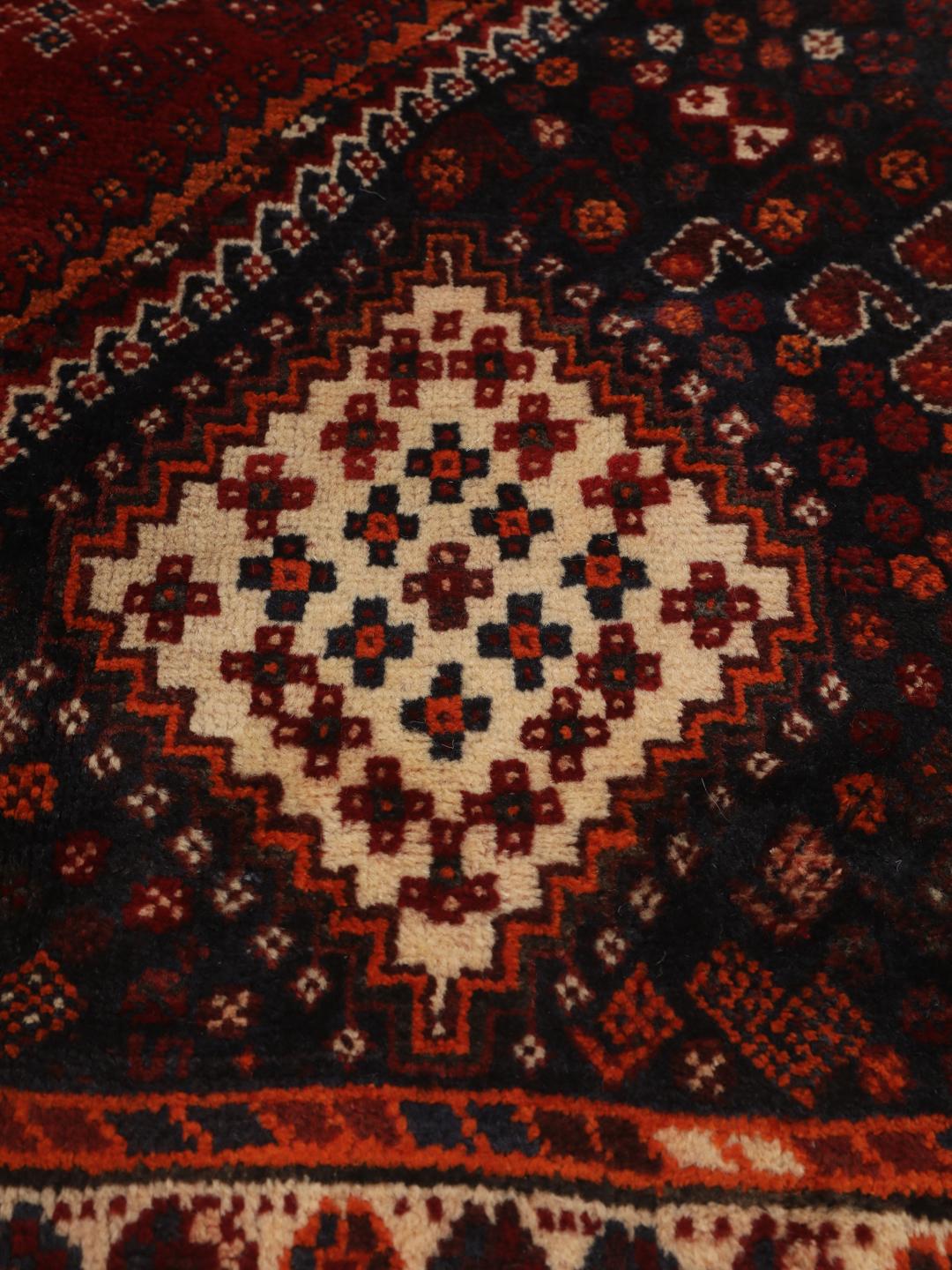 Hand-knotted Qashqai rug from the Middle East with a red field and geometric patterns