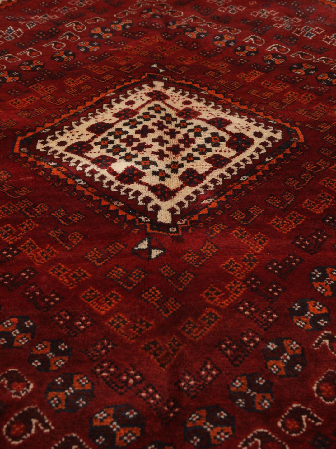 Hand-knotted Qashqai rug from the Middle East with a red field and geometric patterns