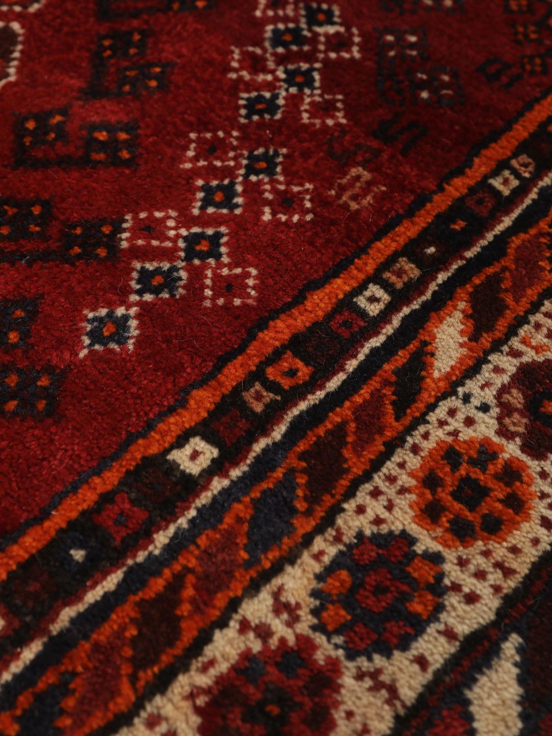 Hand-knotted Qashqai rug from the Middle East with a red field and geometric patterns
