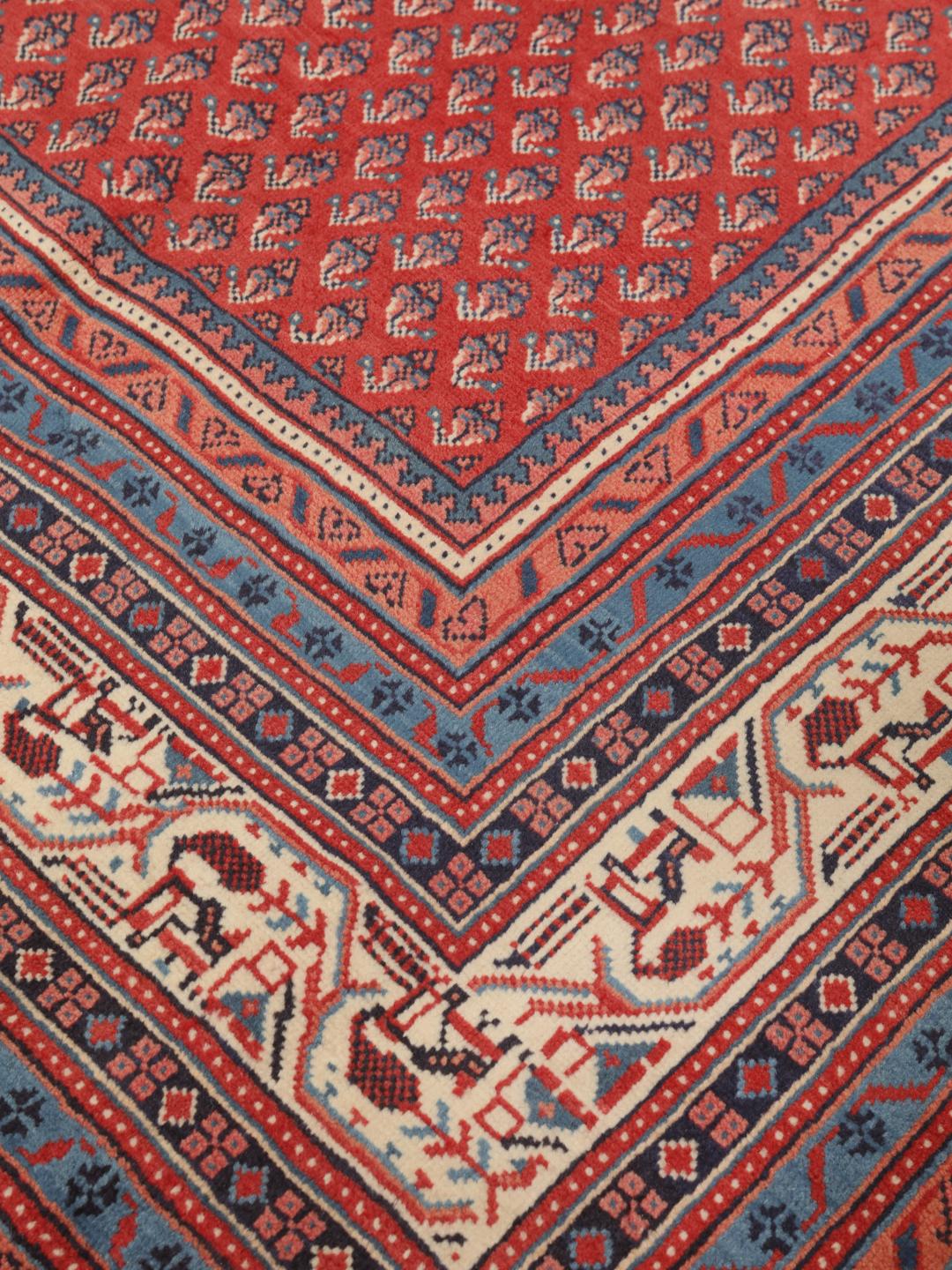 A large hand-knotted Sarough Mir rug with a deep red field and intricate border from the Middle East.