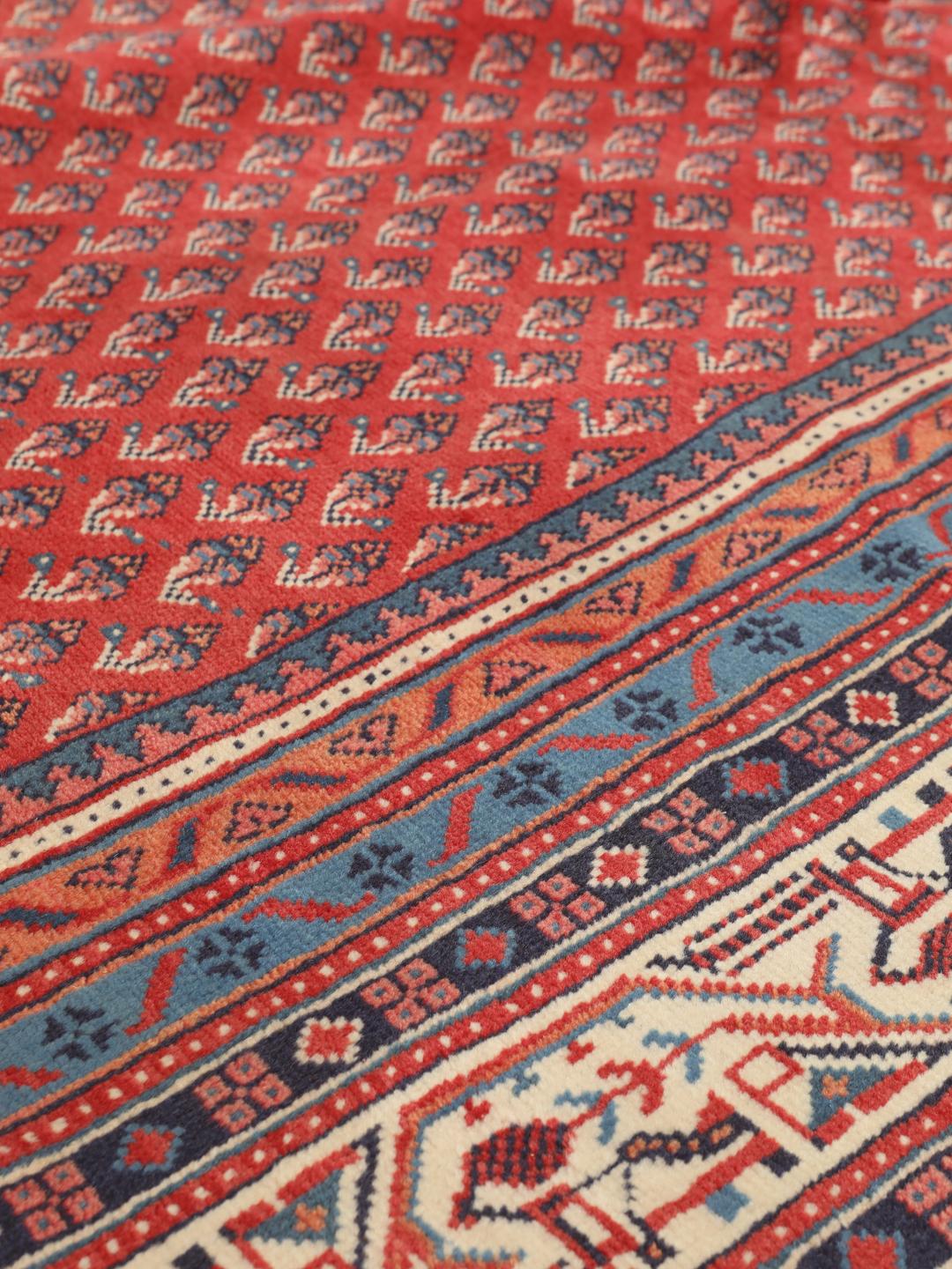 A large hand-knotted Sarough Mir rug with a deep red field and intricate border from the Middle East.
