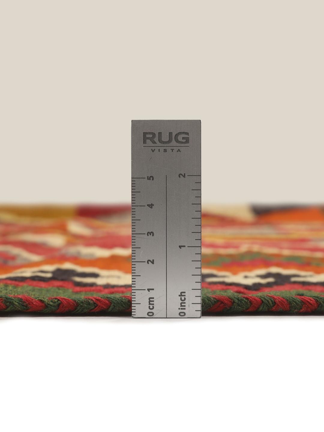 Et håndvævet vintage-kelimtæppe fra Mellemøsten med en rød flade og geometriske motiver.