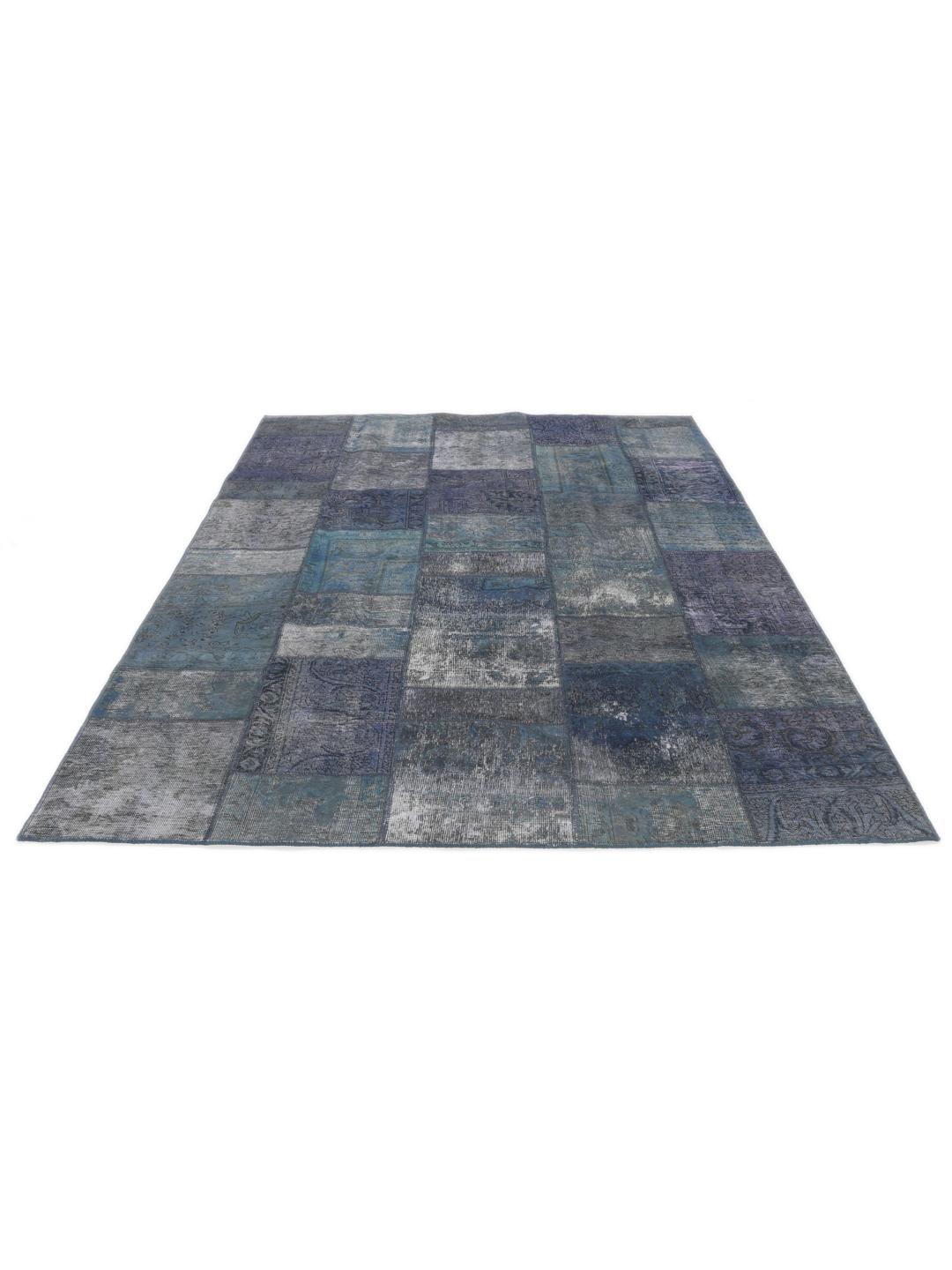 Een groot rechthoekig patchwork vloerkleed met diverse tinten donkerblauw en grijs, handgemaakt in het Midden-Oosten.