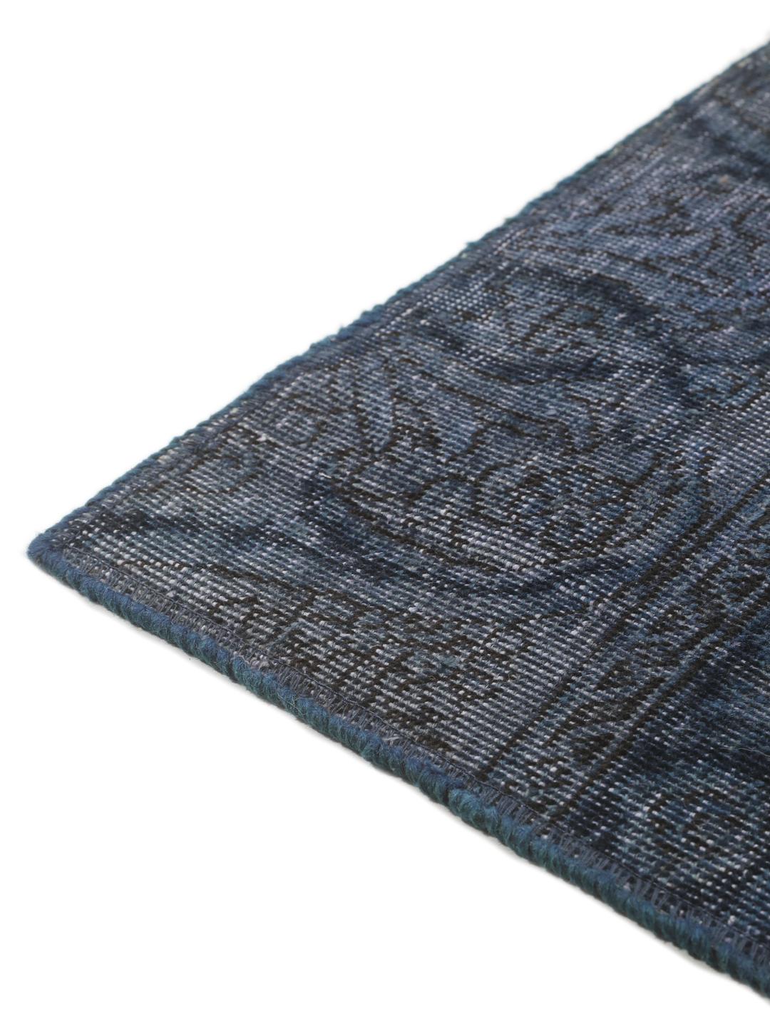 Een groot rechthoekig patchwork vloerkleed met diverse tinten donkerblauw en grijs, handgemaakt in het Midden-Oosten.