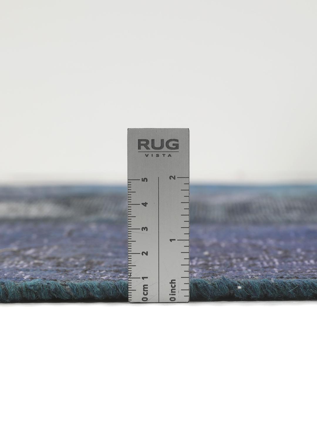 Een groot rechthoekig patchwork vloerkleed met diverse tinten donkerblauw en grijs, handgemaakt in het Midden-Oosten.