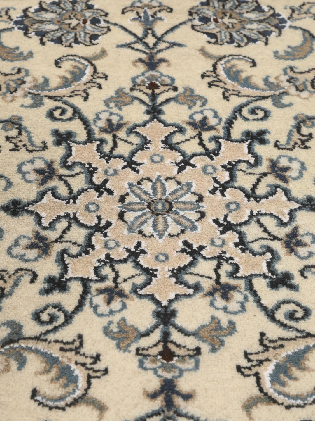 Hand-knotted Nain rug from the Middle East with a light beige field and blue floral motifs