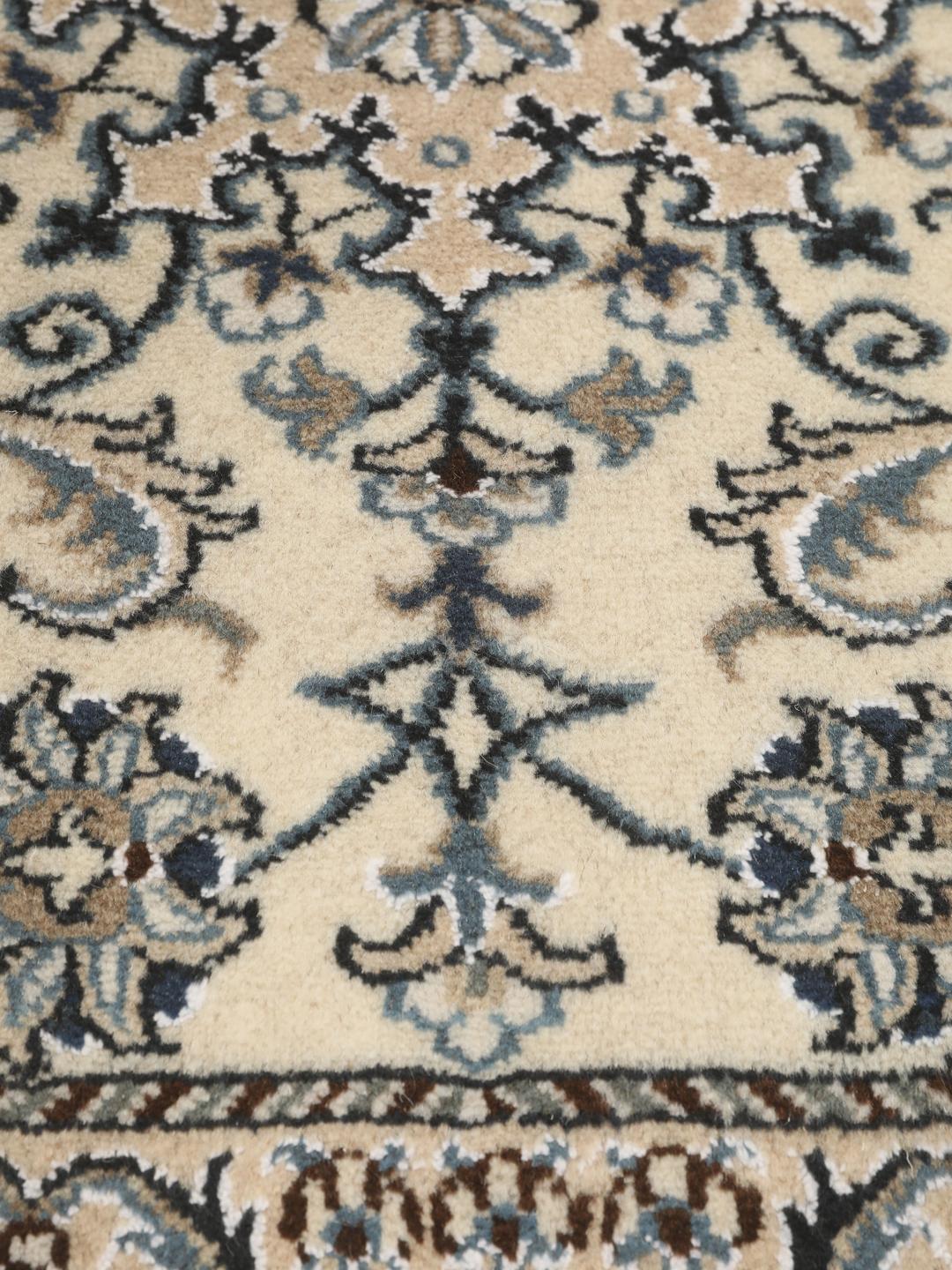 Hand-knotted Nain rug from the Middle East with a light beige field and blue floral motifs