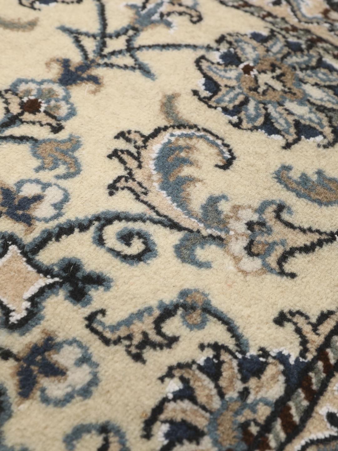 Hand-knotted Nain rug from the Middle East with a light beige field and blue floral motifs