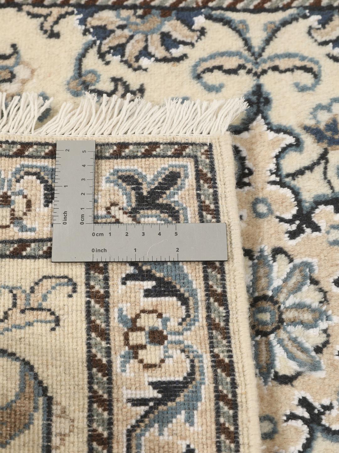 Hand-knotted Nain rug from the Middle East with a light beige field and blue floral motifs