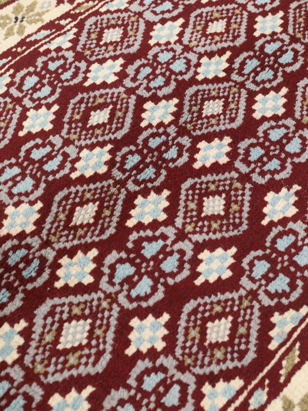 Hand-knotted Beluch rug with geometric motifs in red, blue, and cream
