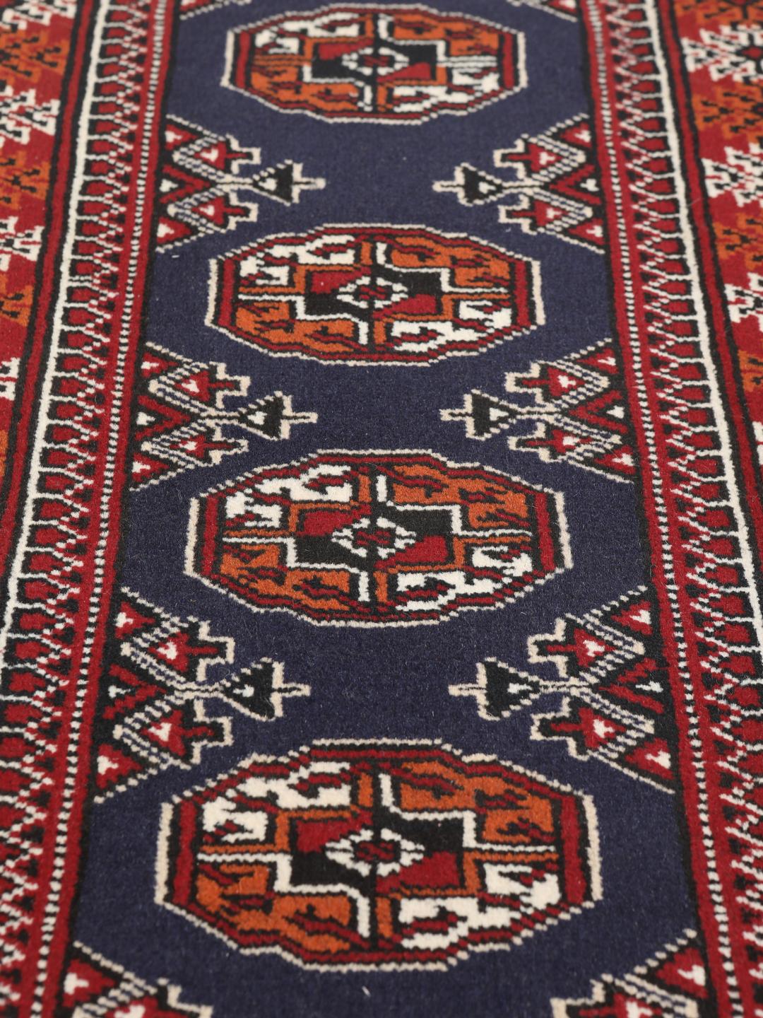 Hand-knotted Turkaman rug from the Middle East in dark-red and dark-blue tones.