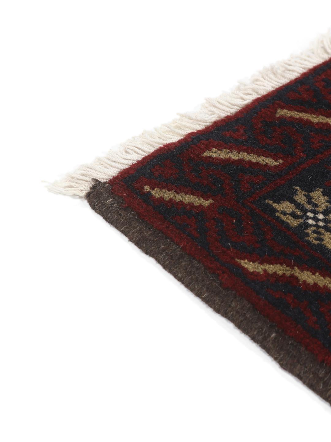 Et håndknyttet Baluch-tæppe fra Mellemøsten med et mørkerødt og blåt geometrisk design.