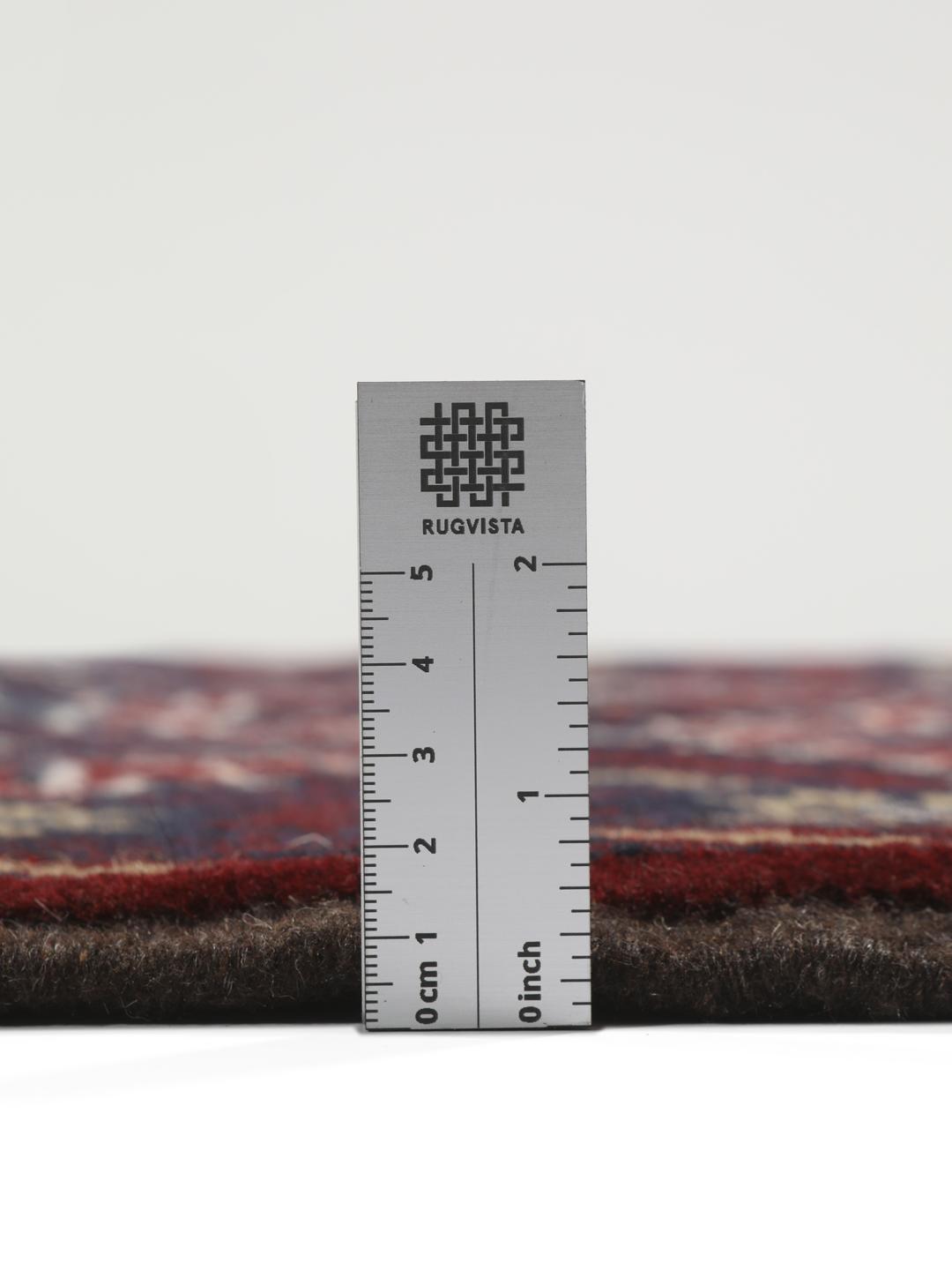 Et håndknyttet Baluch-tæppe fra Mellemøsten med et mørkerødt og blåt geometrisk design.