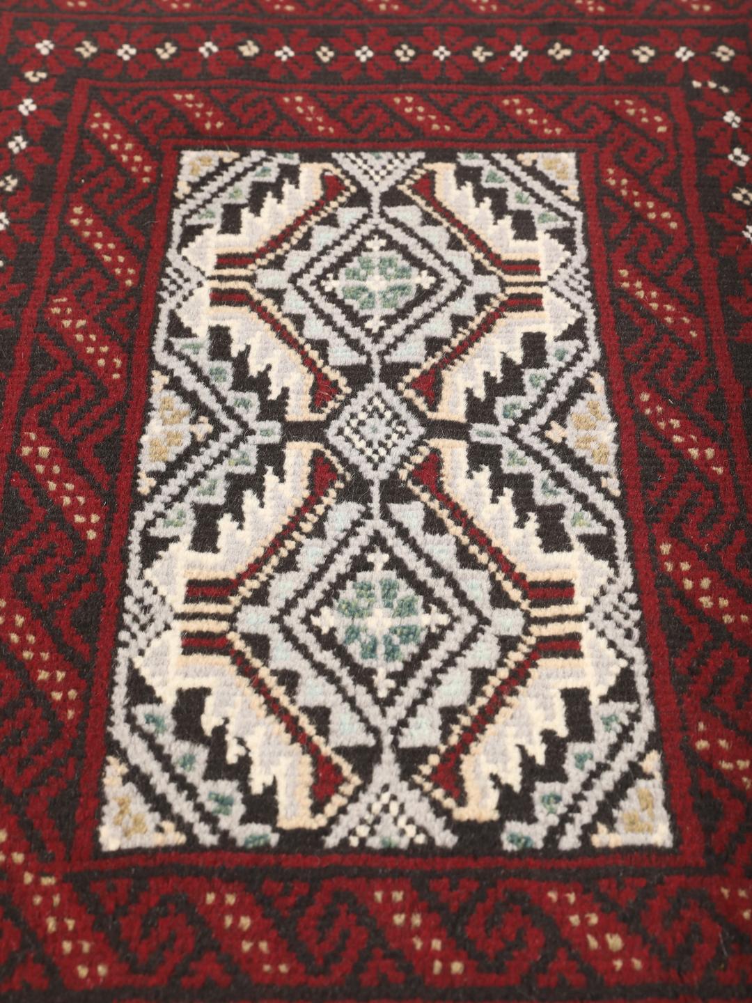 Ein handgeknüpfter Beluch-Teppich mit dunkelrotem und schwarzem Feld aus dem Nahen Osten.