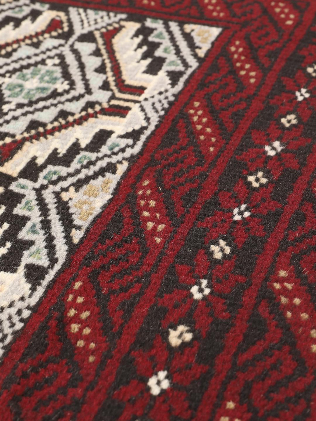 Ein handgeknüpfter Beluch-Teppich mit dunkelrotem und schwarzem Feld aus dem Nahen Osten.