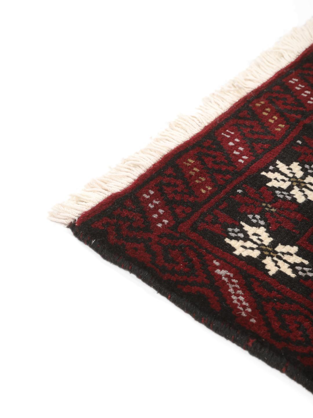 Hand-knotted Middle Eastern Beluch rug in dark red with floral and geometric patterns.