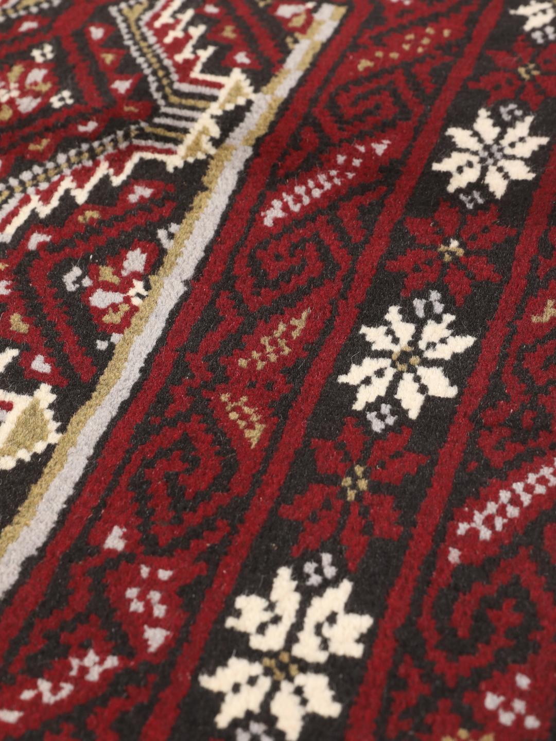 Hand-knotted Middle Eastern Beluch rug in dark red with floral and geometric patterns.
