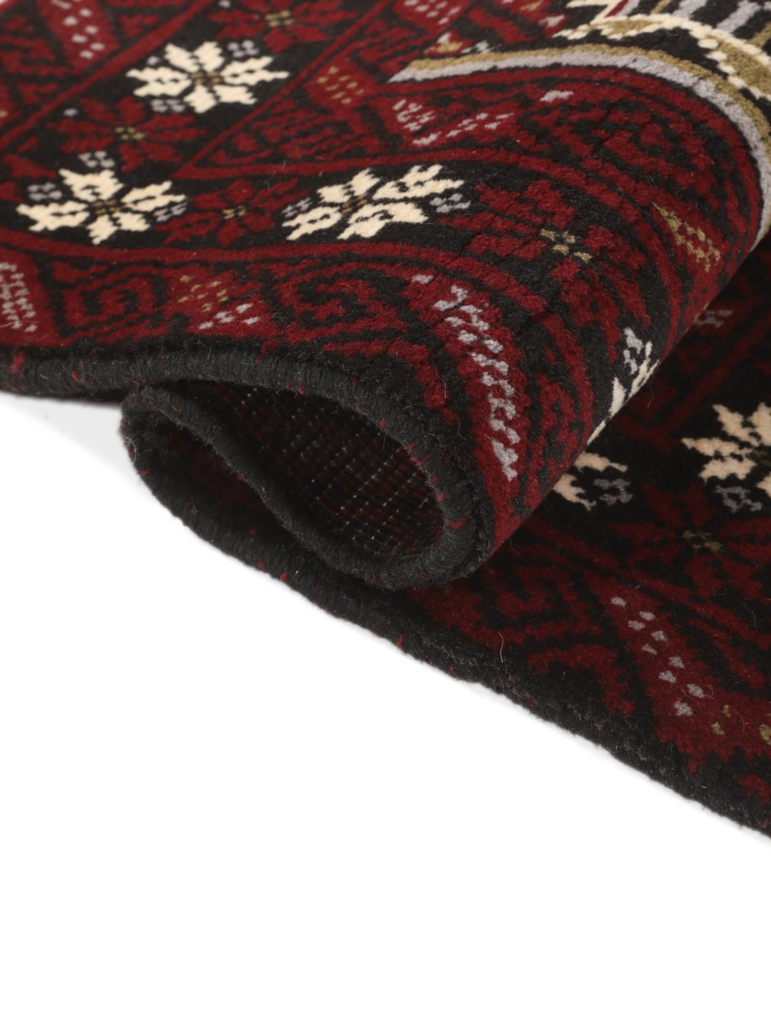 Hand-knotted Middle Eastern Beluch rug in dark red with floral and geometric patterns.