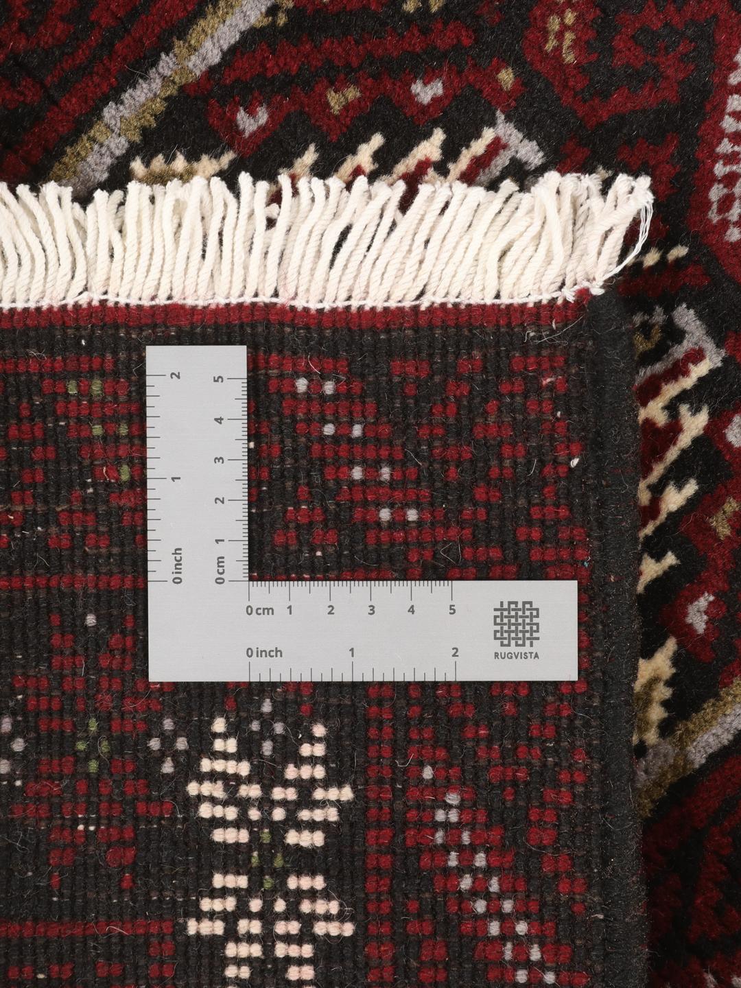 Hand-knotted Middle Eastern Beluch rug in dark red with floral and geometric patterns.