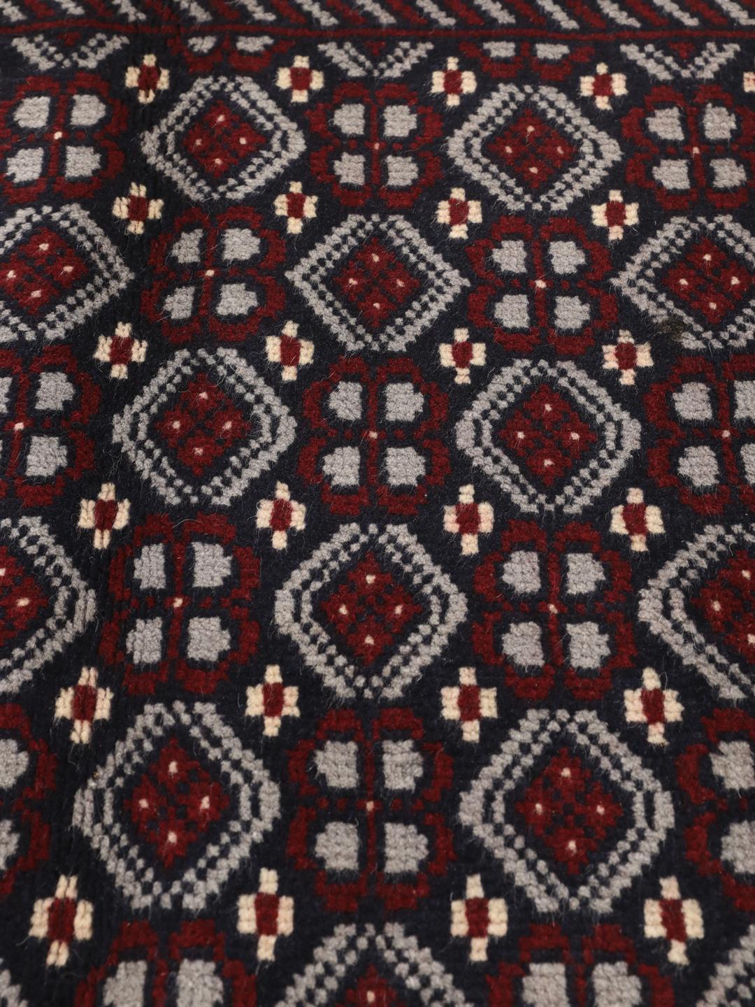 Hand-knotted Baluch rug with geometric tribal patterns in dark blue and red