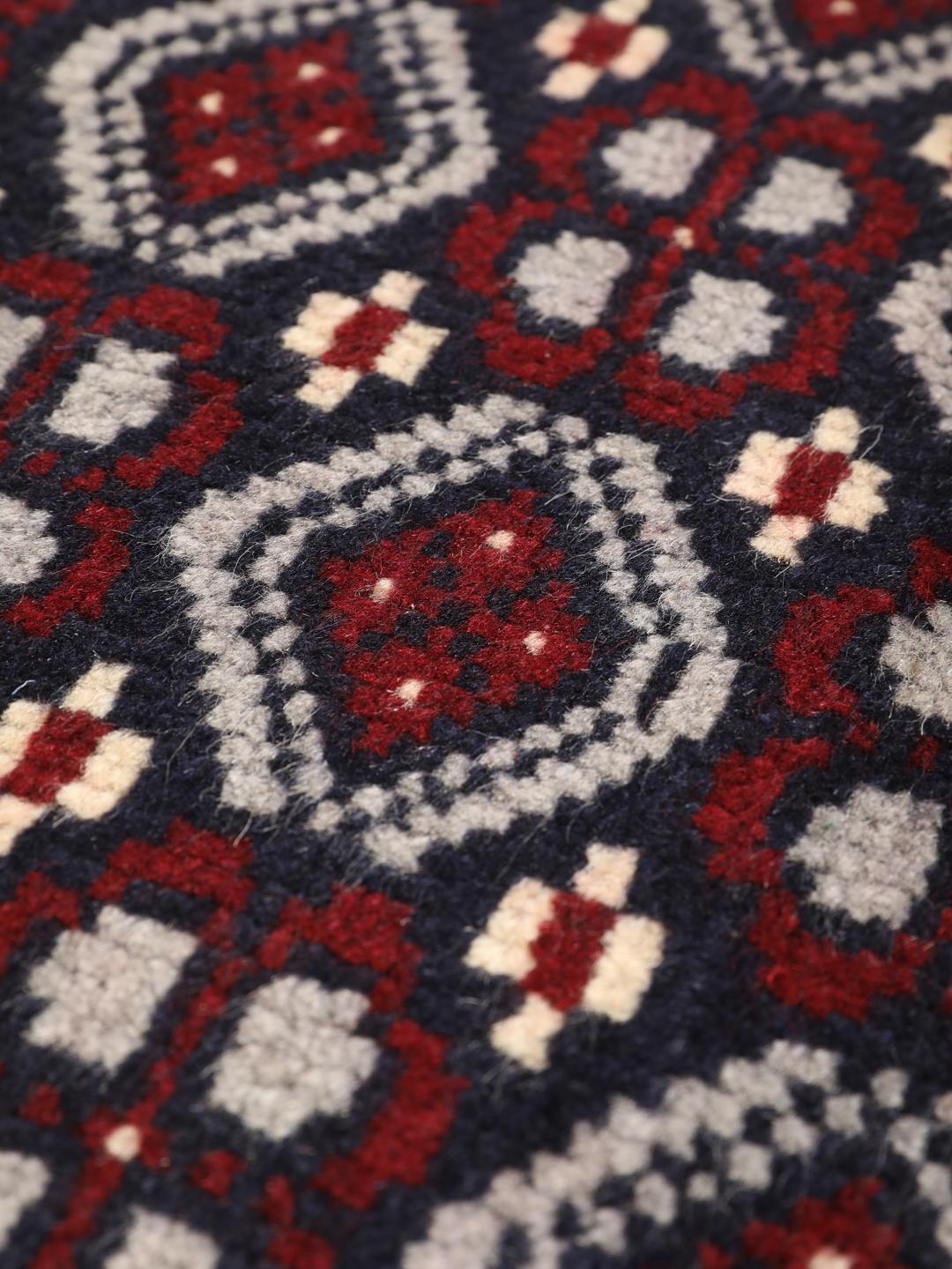 Hand-knotted Baluch rug with geometric tribal patterns in dark blue and red