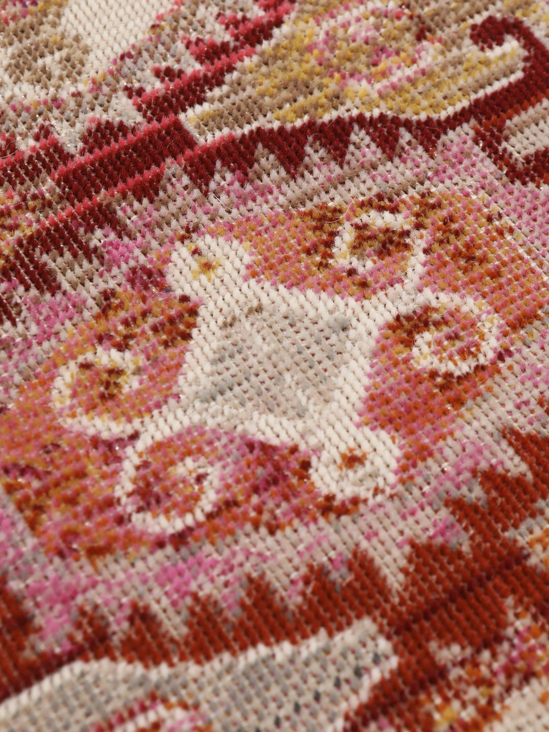 Rundt tæppe med et rødt og pink geometrisk mønster