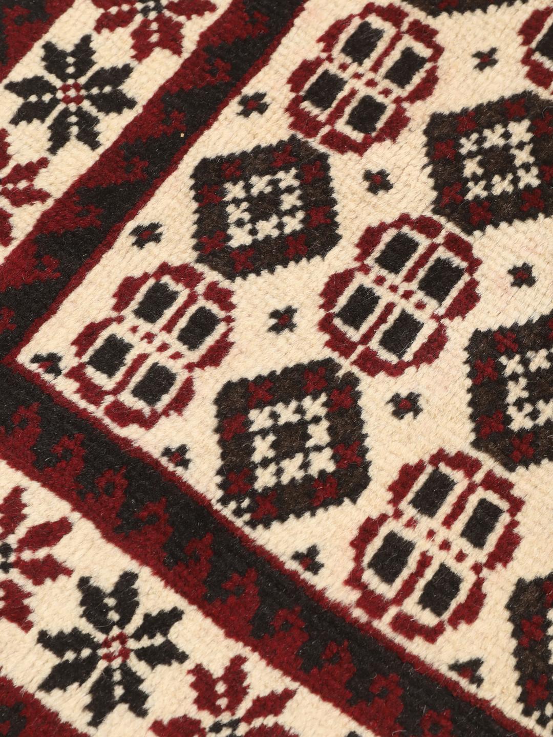 A hand-knotted Baluch rug from the Middle East featuring a red and beige geometric pattern.