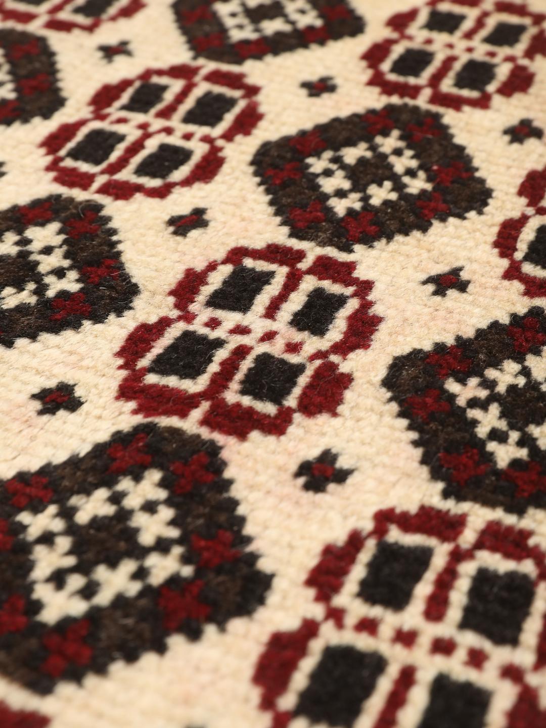 A hand-knotted Baluch rug from the Middle East featuring a red and beige geometric pattern.