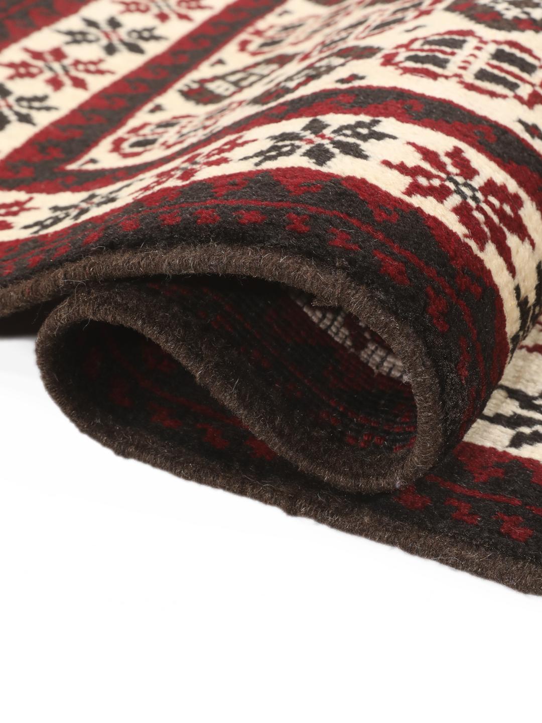 A hand-knotted Baluch rug from the Middle East featuring a red and beige geometric pattern.