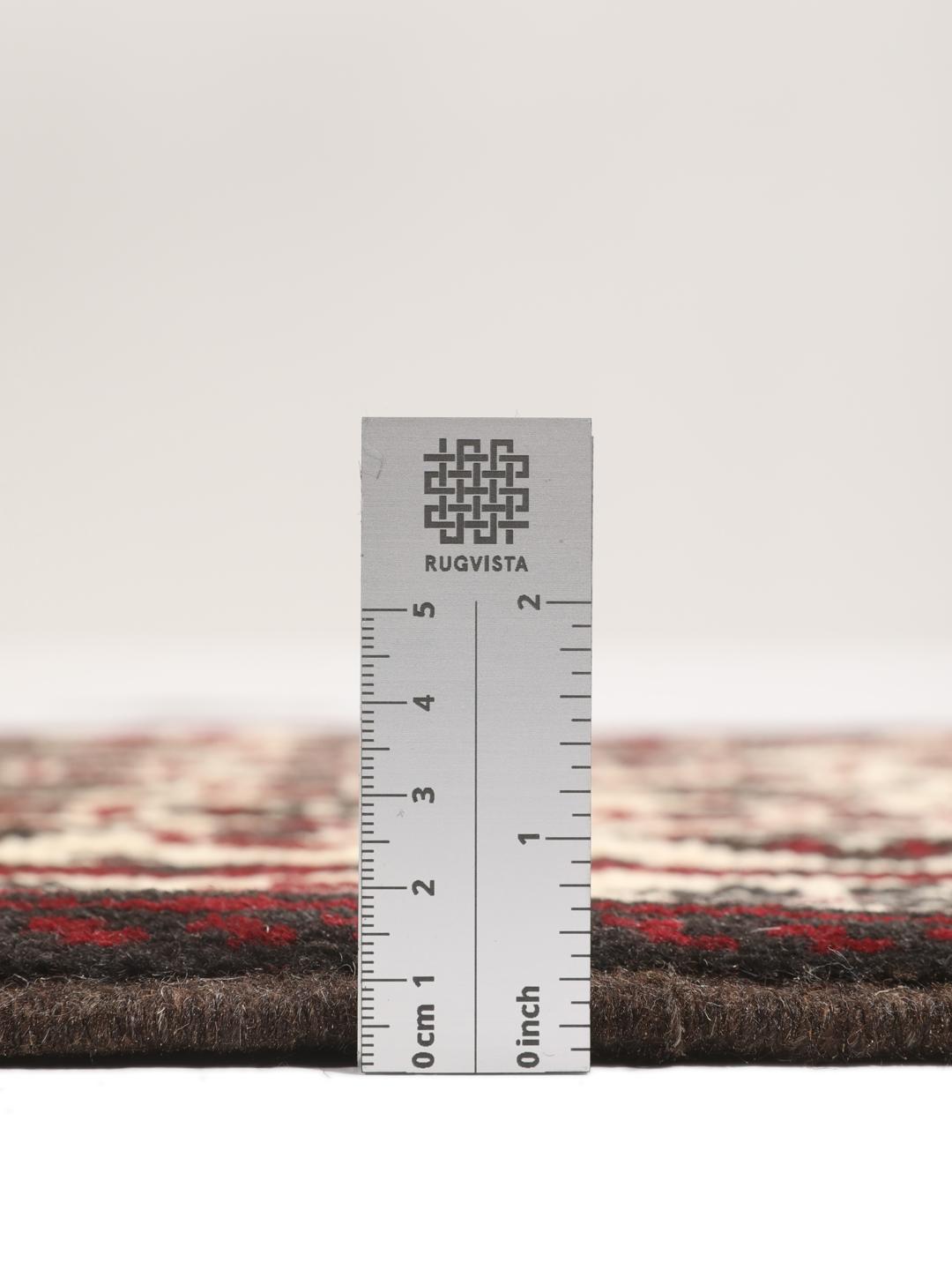 A hand-knotted Baluch rug from the Middle East featuring a red and beige geometric pattern.
