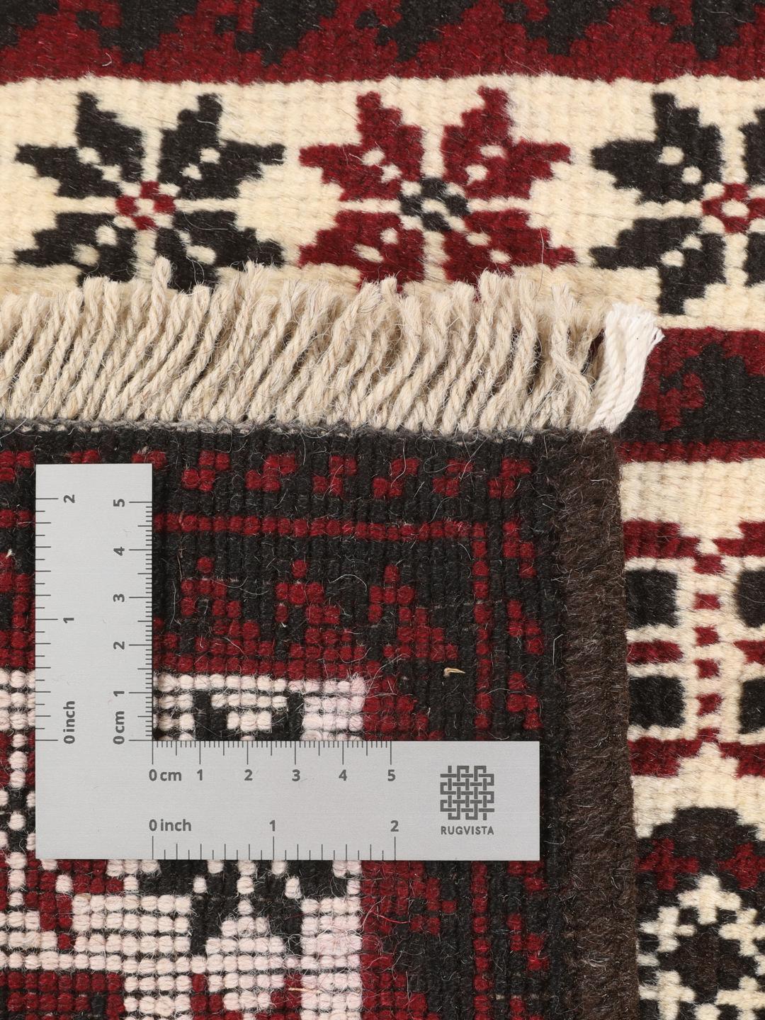 A hand-knotted Baluch rug from the Middle East featuring a red and beige geometric pattern.