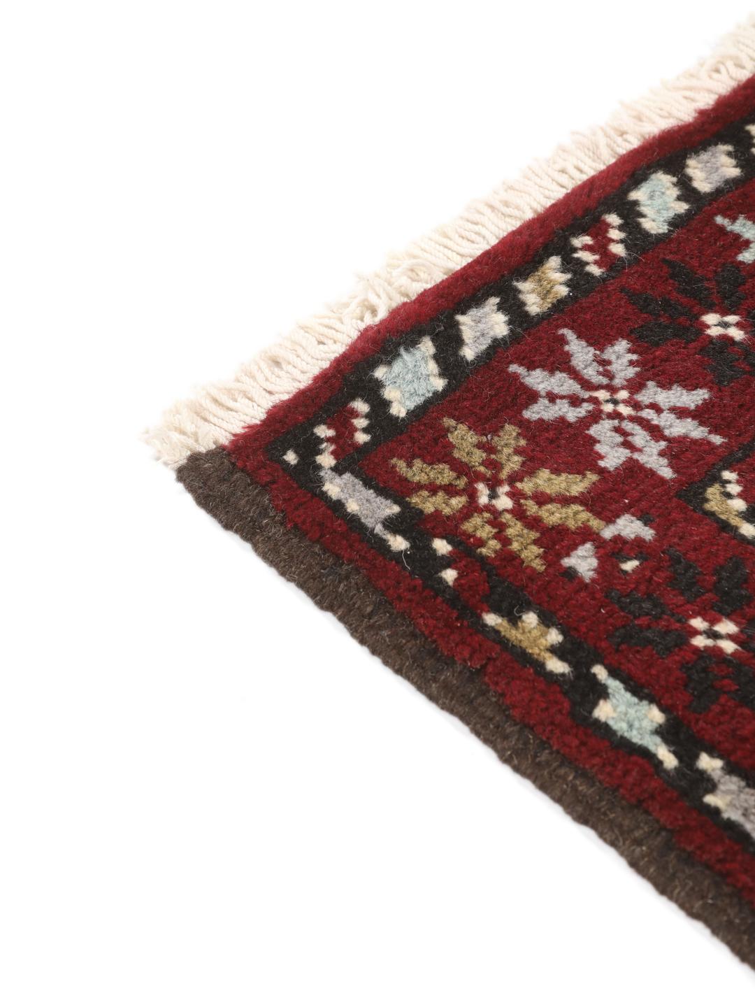 Hand-knotted Baluch rug in dark-red and black with traditional tribal geometric patterns