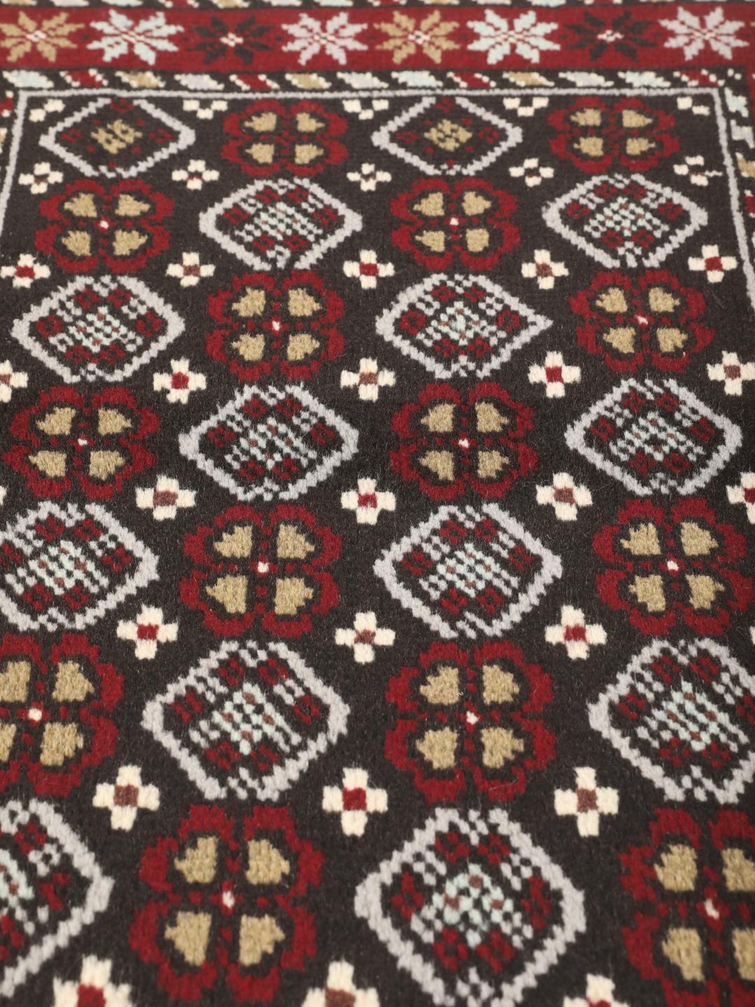 Hand-knotted Baluch rug in dark-red and black with traditional tribal geometric patterns