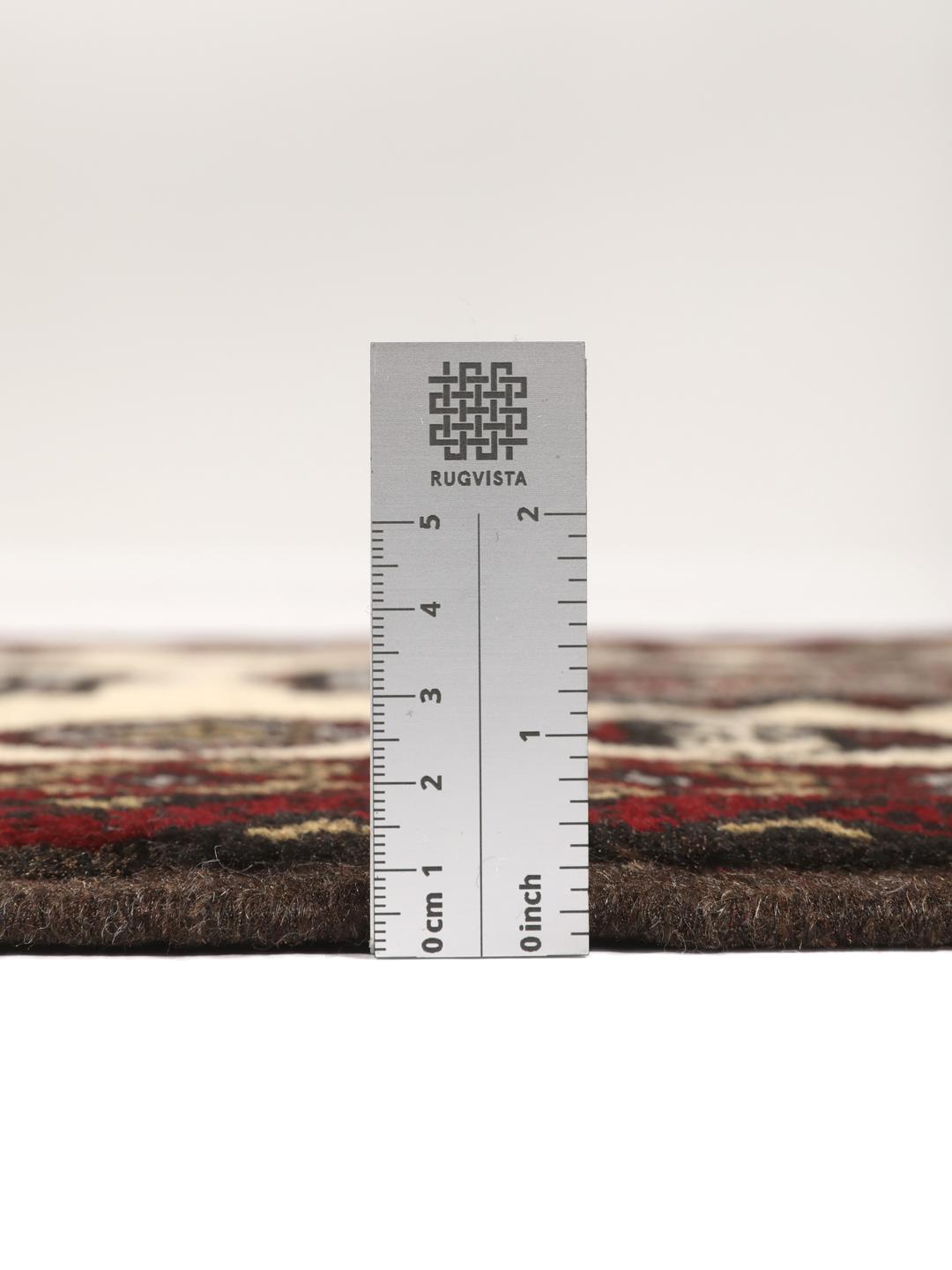 Et håndknyttet Baluch-tæppe fra Mellemøsten med et mørkerødt og cremefarvet geometrisk design.