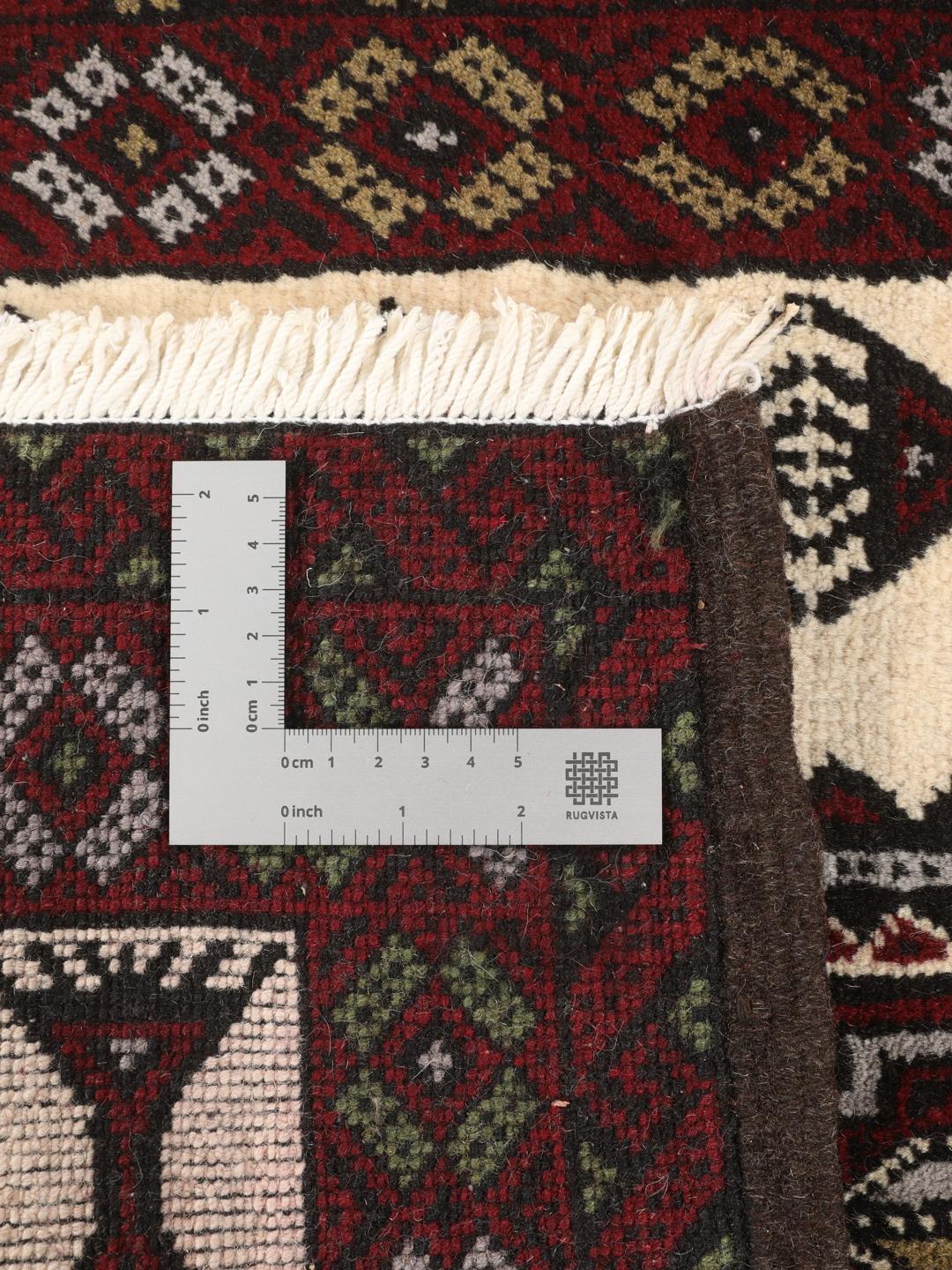Et håndknyttet Baluch-tæppe fra Mellemøsten med et mørkerødt og cremefarvet geometrisk design.