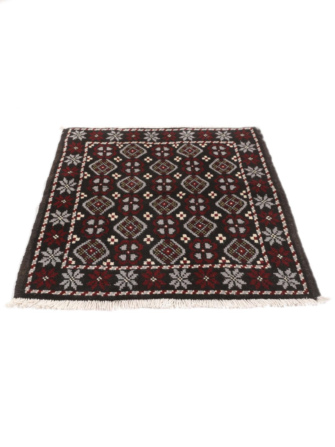 A hand-knotted Baluch rug from the Middle East featuring a black, red, and grey geometric pattern.