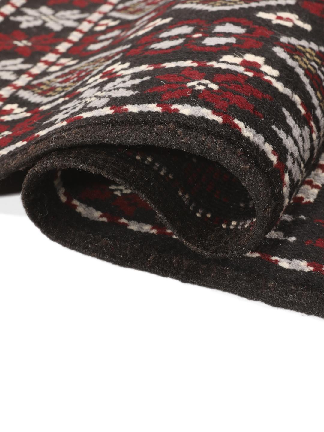 A hand-knotted Baluch rug from the Middle East featuring a black, red, and grey geometric pattern.