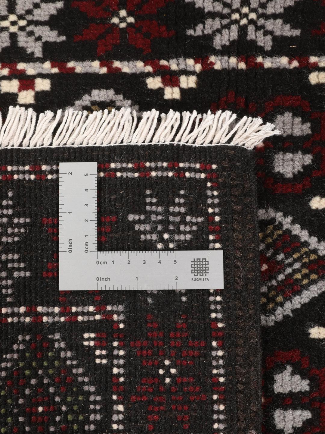 A hand-knotted Baluch rug from the Middle East featuring a black, red, and grey geometric pattern.