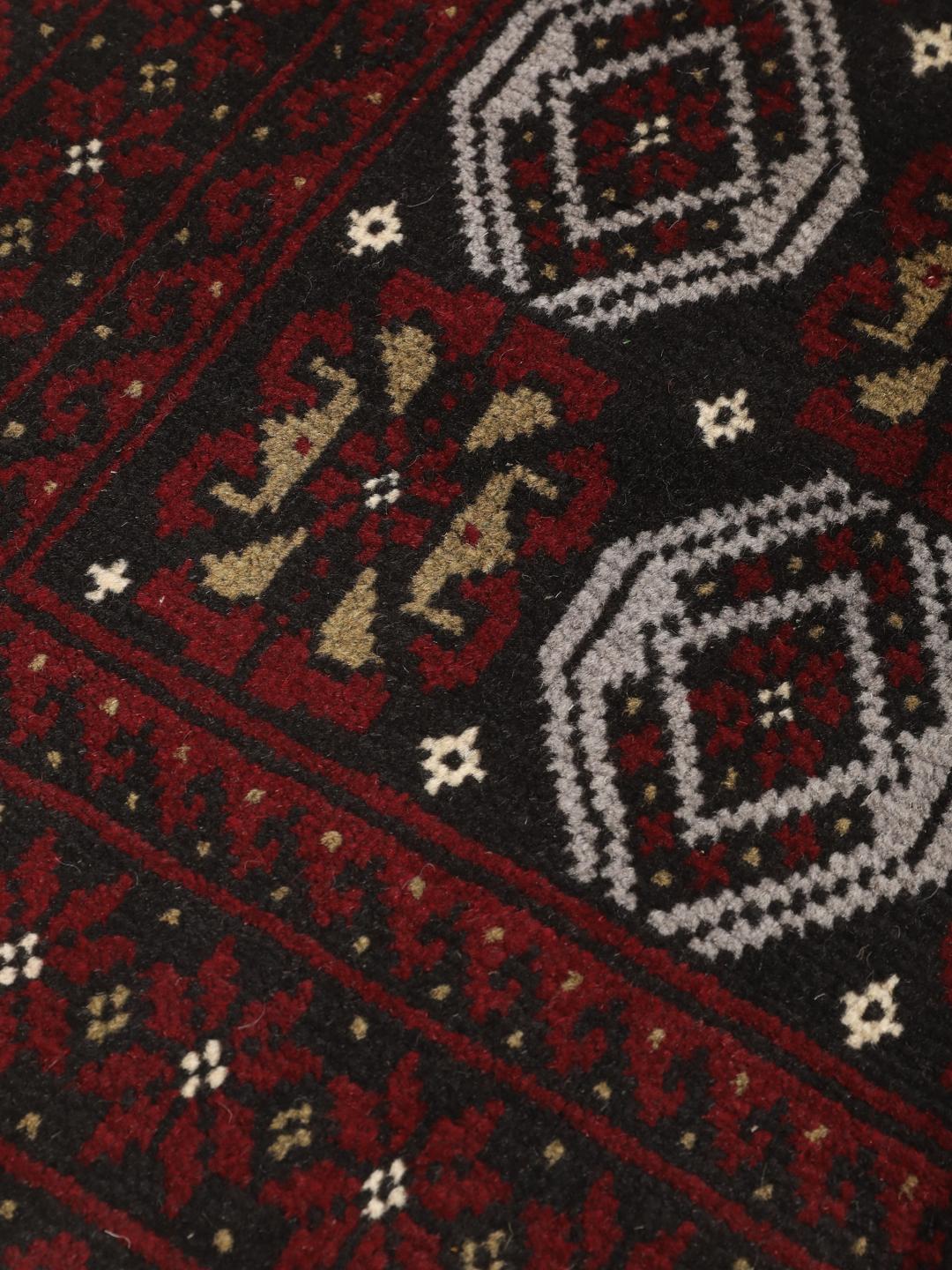 A small, one-of-a-kind Baluch rug from the Middle East with a dark-red and black geometric pattern.
